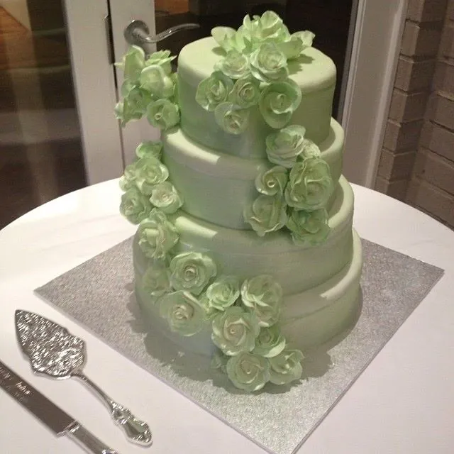 Torta a tre piani verde menta con cascata di rose di zucchero lungo il fianco