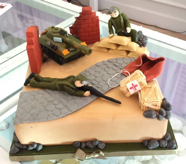Torta rettangolare scenografica con diorama di guerra, soldati, muretto, casse e carro armato