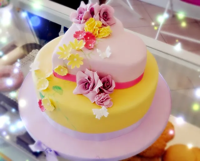 La torta vista di tre quarti, con rose e fiorellini gialli