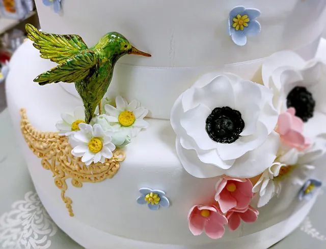 Il colibrì verde con anemoni e fiori azzurri