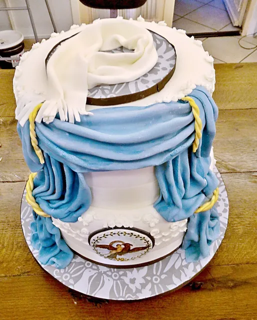 Torta scenografica a due piani con tende azzurre drappeggiate e medaglione dipinto con un'aquila