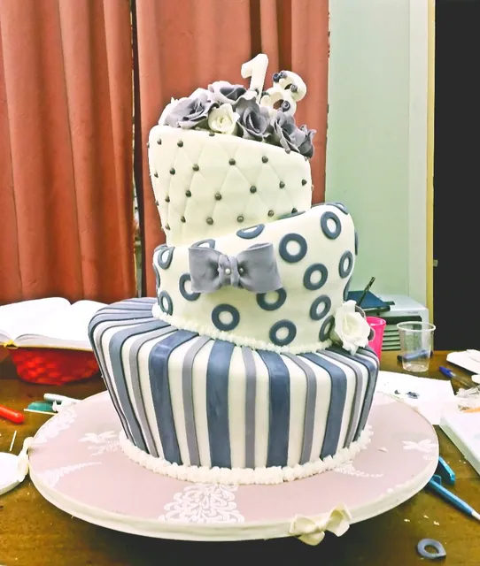 La torta storta vista dal lato, con righe grigie e fiocco