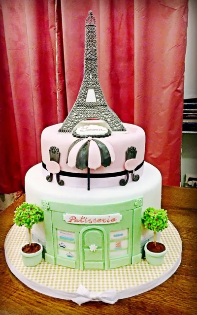 Torta a due piani con Torre Eiffel in zucchero sopra una pasticceria in miniatura verde menta e tendina rosa