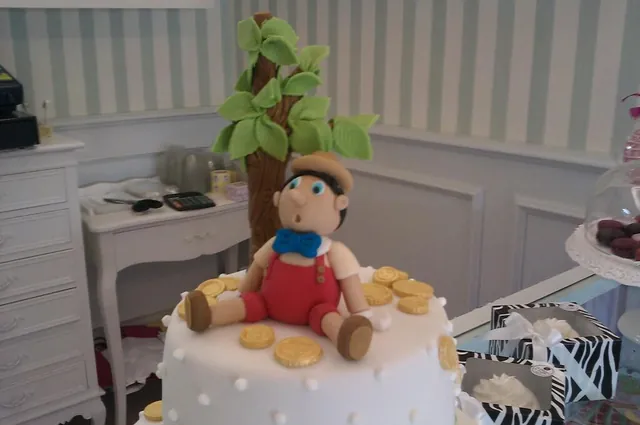 Pinocchio in pasta di zucchero seduto tra le monete d'oro, con l'albero