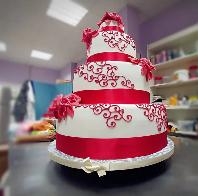 Torta nuziale a quattro piani bianca con arabeschi e nastri fucsia e rose fucsia di zucchero