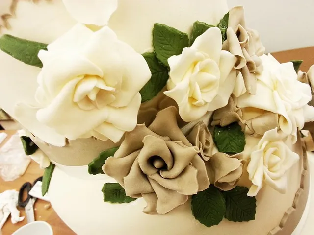 Dettaglio delle rose di zucchero avorio e tortora con le foglie verdi