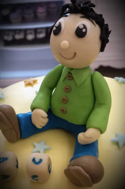 Statuina di bambolotto seduto con camicia verde e dadi colorati