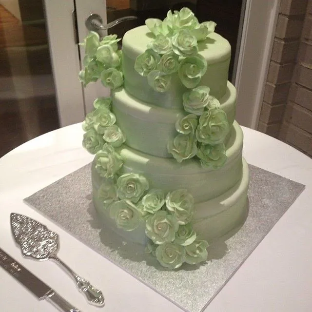 Torta a tre piani verde menta con cascata di rose di zucchero lungo il fianco
