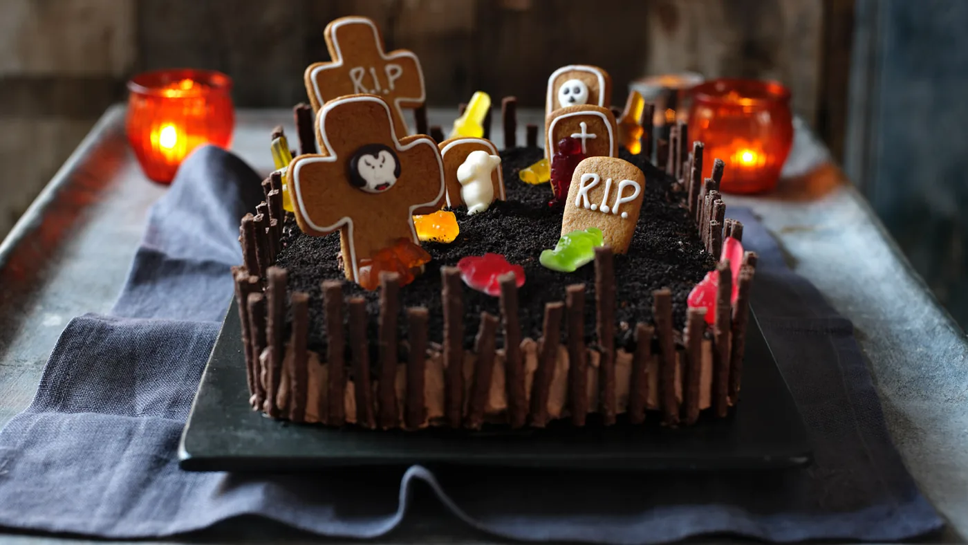 Torta scenografica a forma di cimitero con steccato, lapidi RIP e terra scura