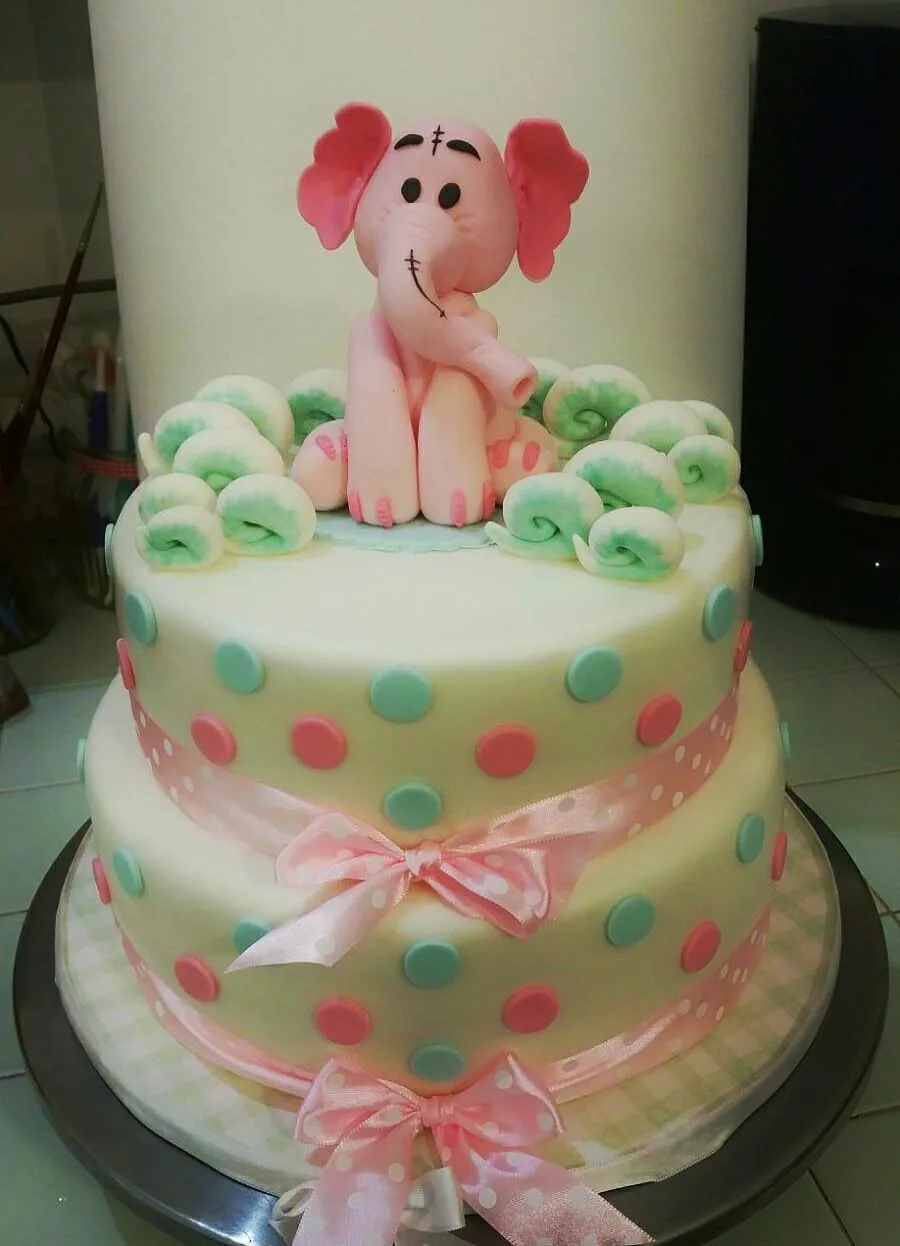 Torta a due piani crema con pois rosa e verde acqua, fiocco rosa e un elefantino di pasta di zucchero in cima