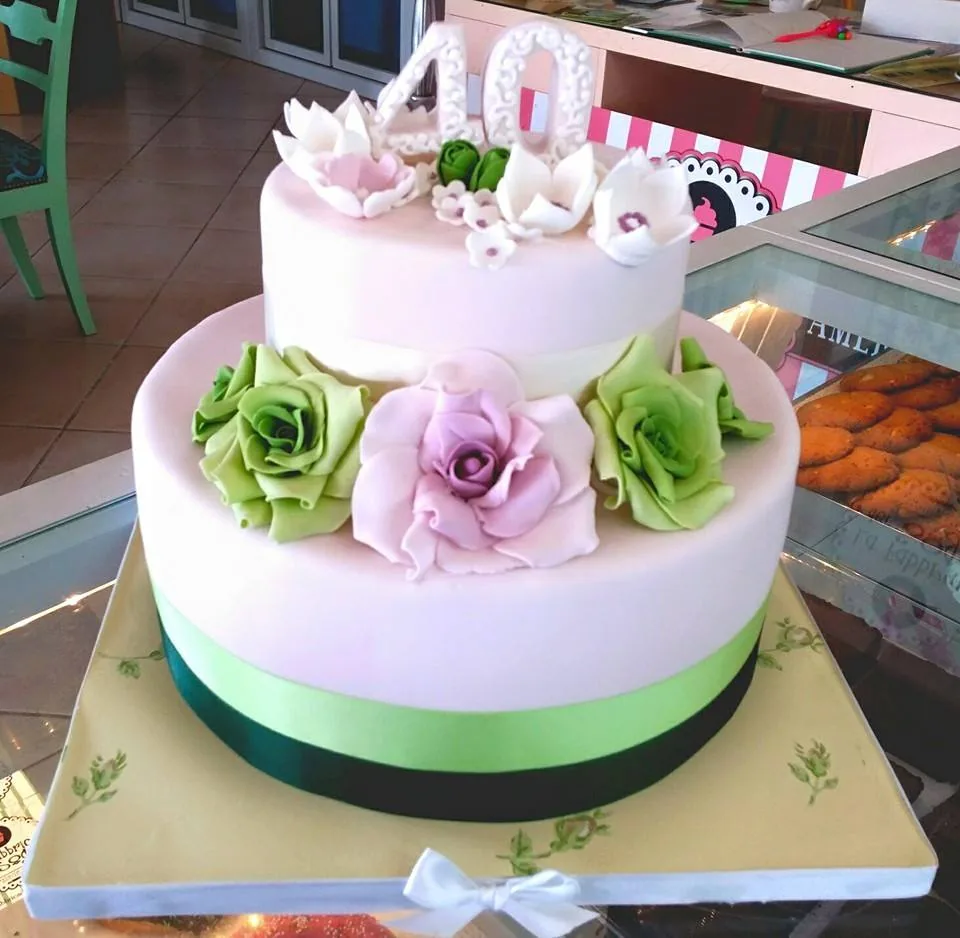 Torta a due piani rosa chiaro con rose verdi e lilla, nastro verde e numero 40 con fiori in zucchero